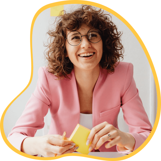A woman in a pink blazer smiling while taking notes on post-its