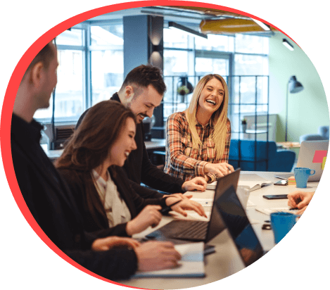 A happy group of people working together at a table with laptops